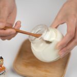 Ritaglia l'uomo che prende yogurt naturale con il cucchiaio dal barattolo