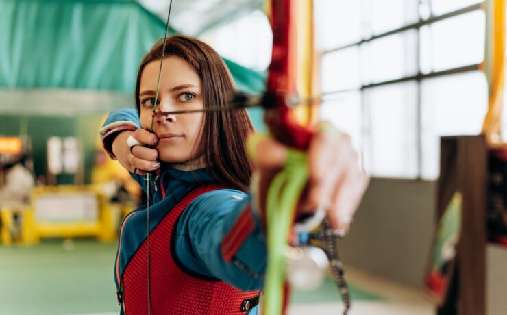 Beautiful Woman Shooting a Bow and Arrow archery sport focus attention concentration mind health