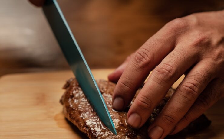 Person Slicing Meat on Brown Chopping Board knife steack