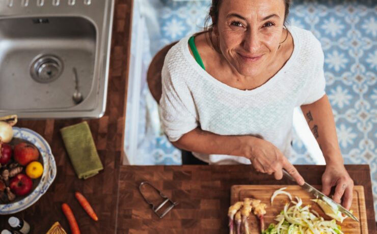 donna in camicia bianca con scollo rotondo che tiene il sorriso della cucina del tagliere di legno marrone