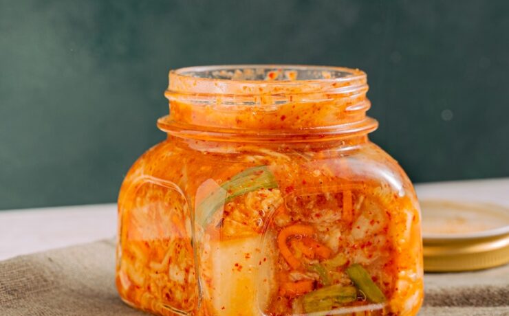 Barattolo di vetro trasparente con Kimchi accanto alle bacchette di legno verdure fermentate