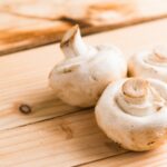 Tre funghi bianchi sulla tavola di legno beige