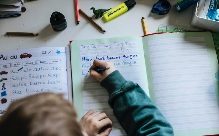 a person writing on a notebook with a pen bambino