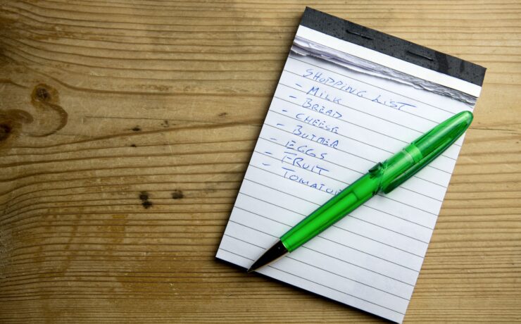 a notepad with a green pen sitting on top of it weekly shopping list grocery food