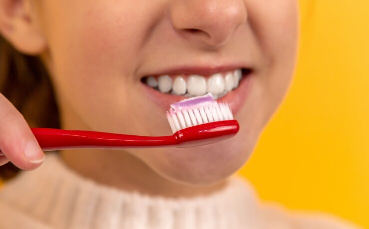 girl with red and white toothbrush in mouth