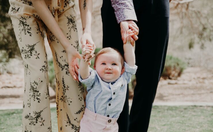 uomo e donna che tengono la mano del bambino che cammina sul campo di erba padre madre