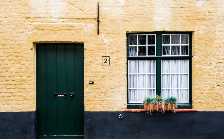 Facciata di una casa con una porta nera e una finestra laterale