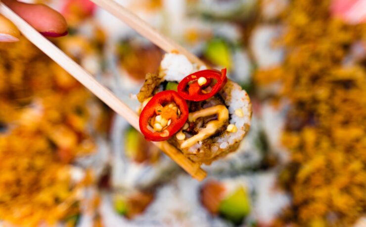 a person holding a chopstick with food on it spicy food exotic