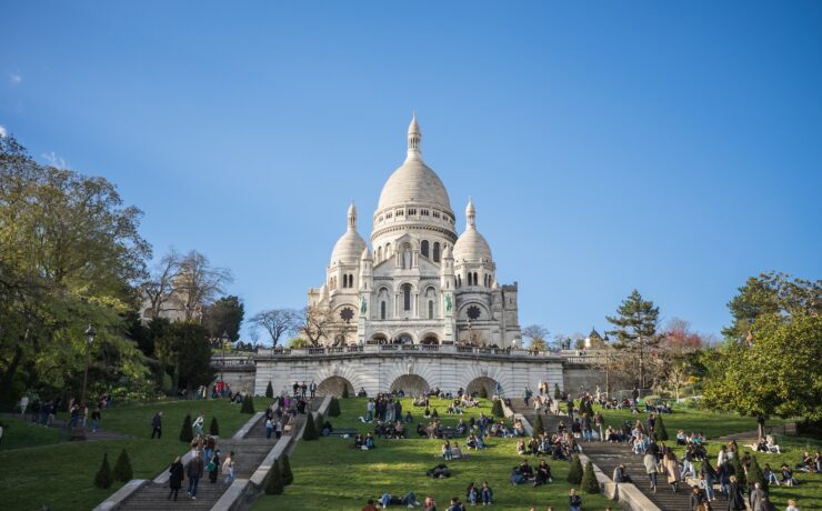 un gruppo di persone sedute sui gradini di fronte a un edificio chiesa sacre-coeur parigi montmartre