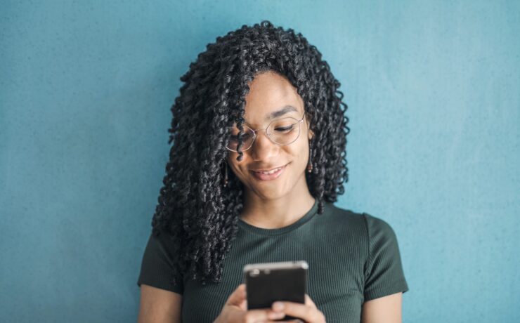 Ragazza con gli occhiali che messaggia con il cellulare in mano