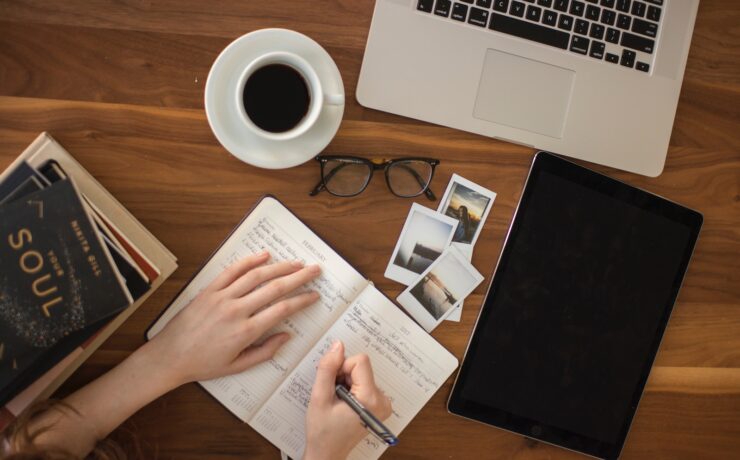 person holding ballpoint pen writing on notebook