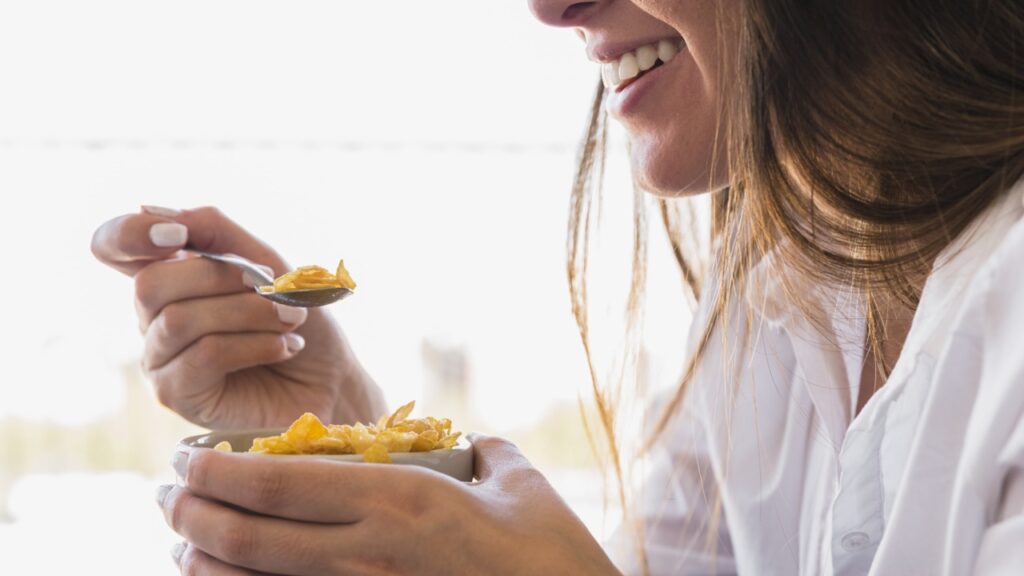 donna che mangia ciotola d'avena per colazione mentre sorride