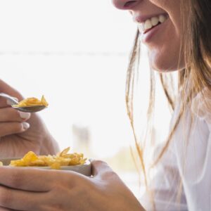 donna che mangia ciotola d'avena per colazione mentre sorride