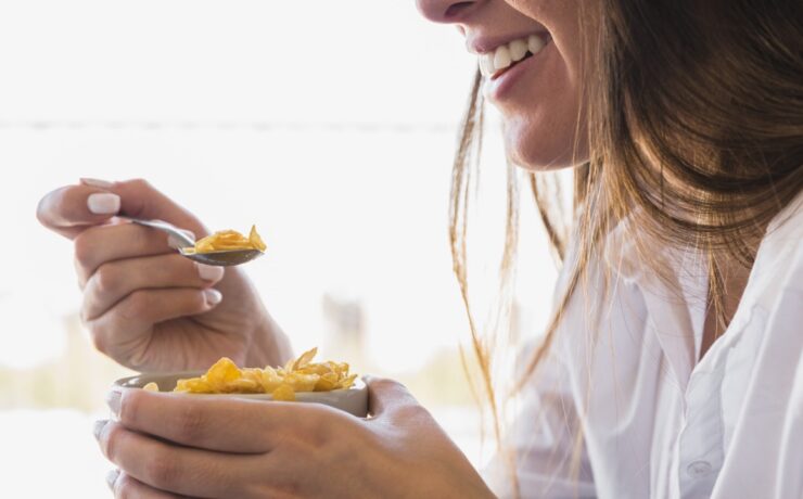 donna che mangia ciotola d'avena per colazione mentre sorride