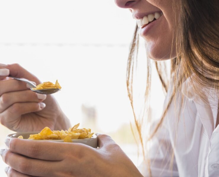 donna che mangia ciotola d'avena per colazione mentre sorride