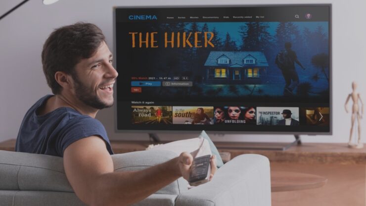 man looking at the television sit on a couch with popcorns