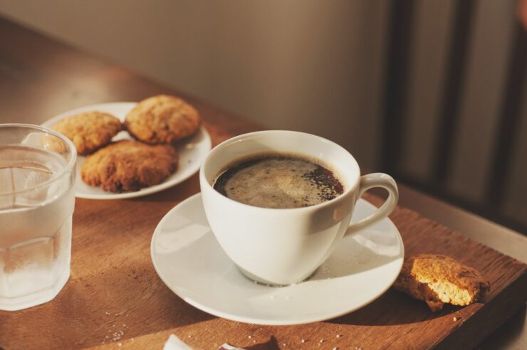 una tazza di caffè, biscotti, un bicchiere d'acqua