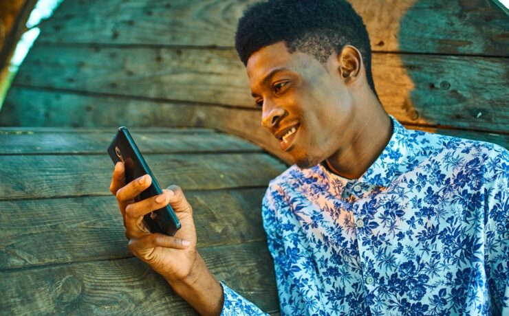 Ragazzo con la camicia che sorride mentre guarda il cellulare