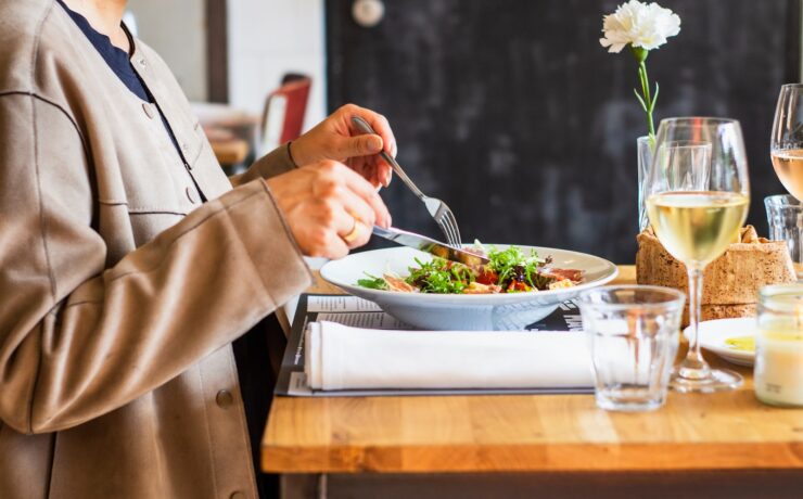 persona che mangia usando forchetta e coltello su un tavolo di legno