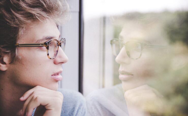 ragazzo che guarda fuori dal finestrino, specchiandosi