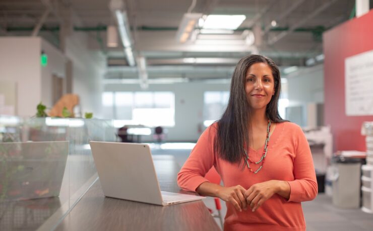 uma mulher de pé ao lado de uma bancada com um notebook