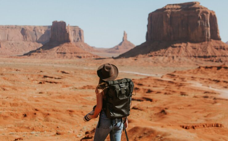 mulher com mochila preta em pé no deserto