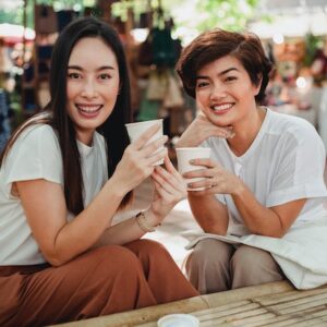 due donne che sorridono mentre bevono un caffé