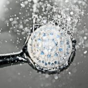 Close-up of a shower head releasing water droplets, creating a crisp and refreshing bathroom scene.