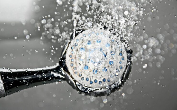 Close-up of a shower head releasing water droplets, creating a crisp and refreshing bathroom scene.