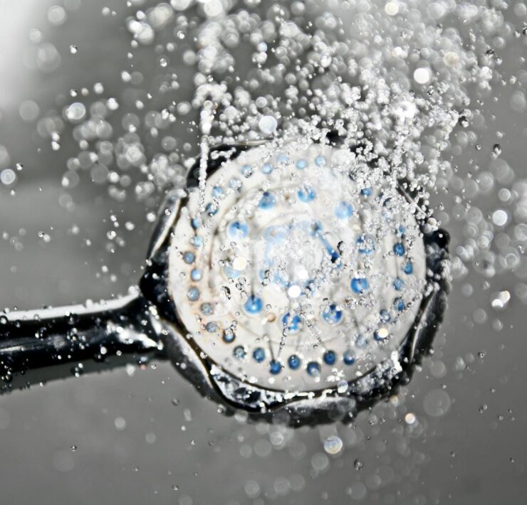 Close-up of a shower head releasing water droplets, creating a crisp and refreshing bathroom scene.