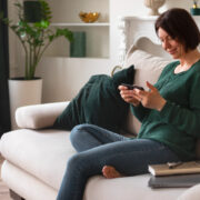 woman sitting on a couch looking at a smartphone
