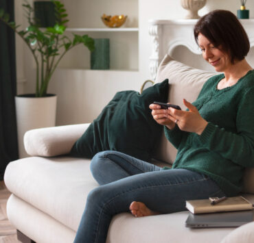 woman sitting on a couch looking at a smartphone