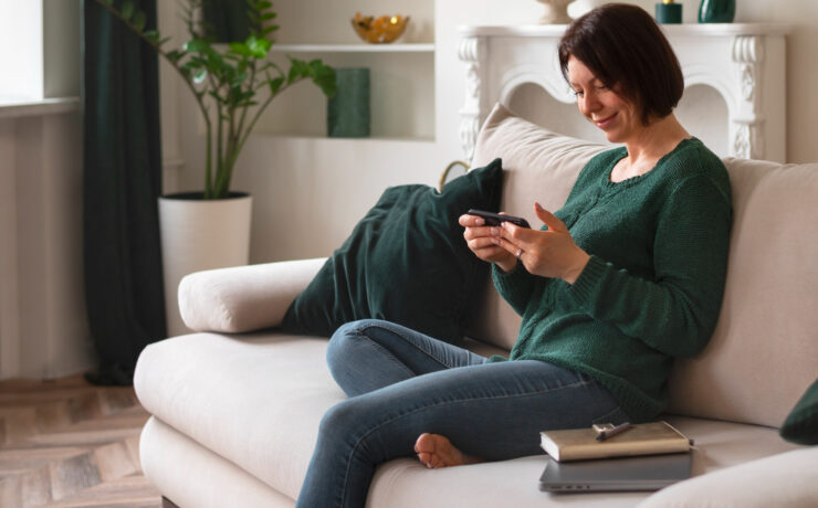 woman sitting on a couch looking at a smartphone