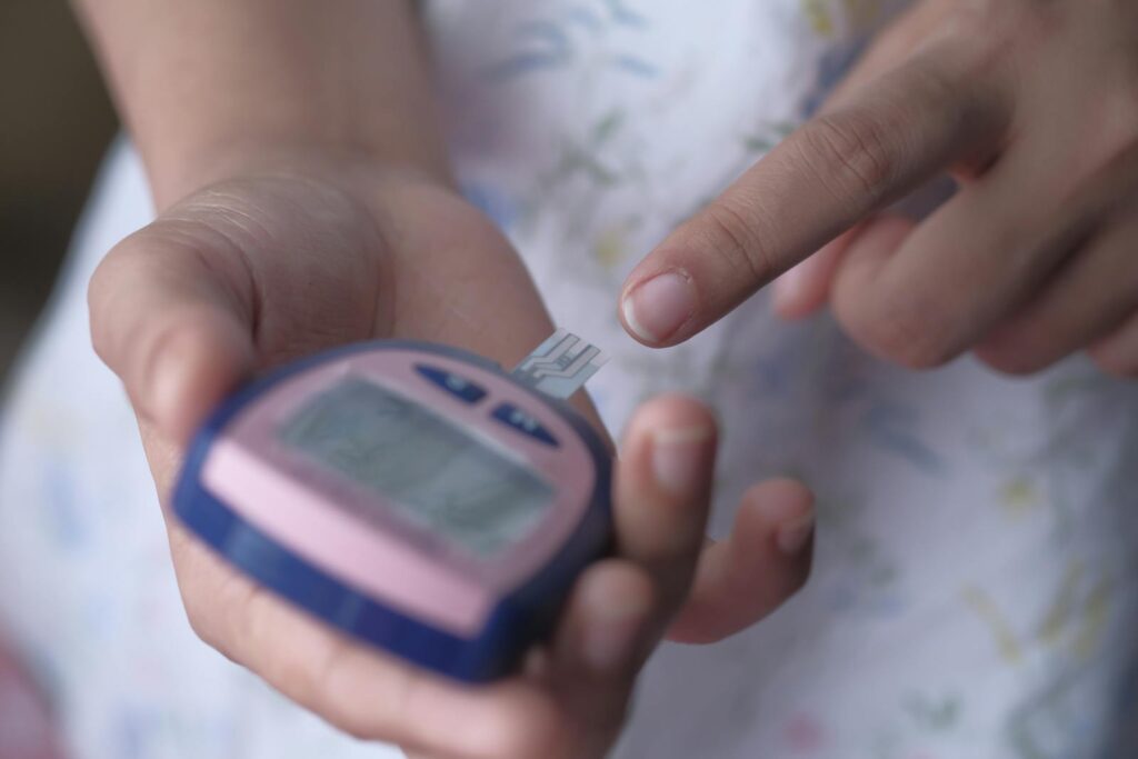 An adult using a glucometer to measure blood glucose levels, illustrating personal healthcare management.