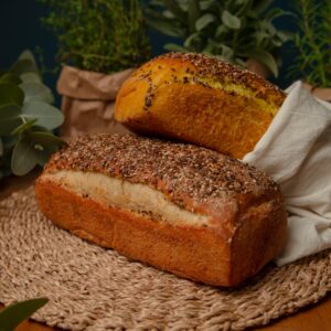 Two artisan loaves of bread surrounded by fresh herbs create a rustic kitchen setting.