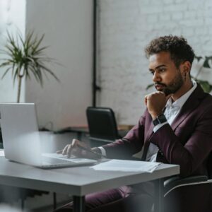 Businessman in corporate attire focused on laptop work in a modern office environment.