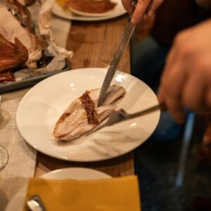 Close-up of slicing turkey breast at a Thanksgiving dinner with wine.