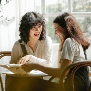 Laughing multiracial female colleagues wearing uniform flipping pages of papers while discussing work together