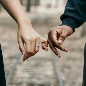 A romantic couple holding hands, symbolizing love and unity on a scenic railtrack.